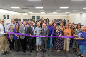 Group surrounding a purple ribbon for a ribbon cutting